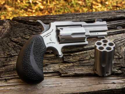 Silver revolver and ammunition on wooden log