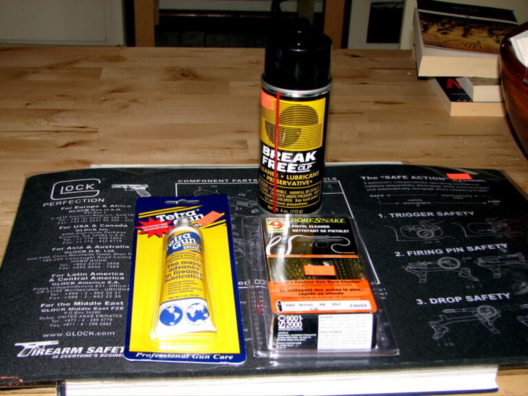 Handgun cleaning kit with solvent, brushes, and cleaning patches on a gun cleaning mat