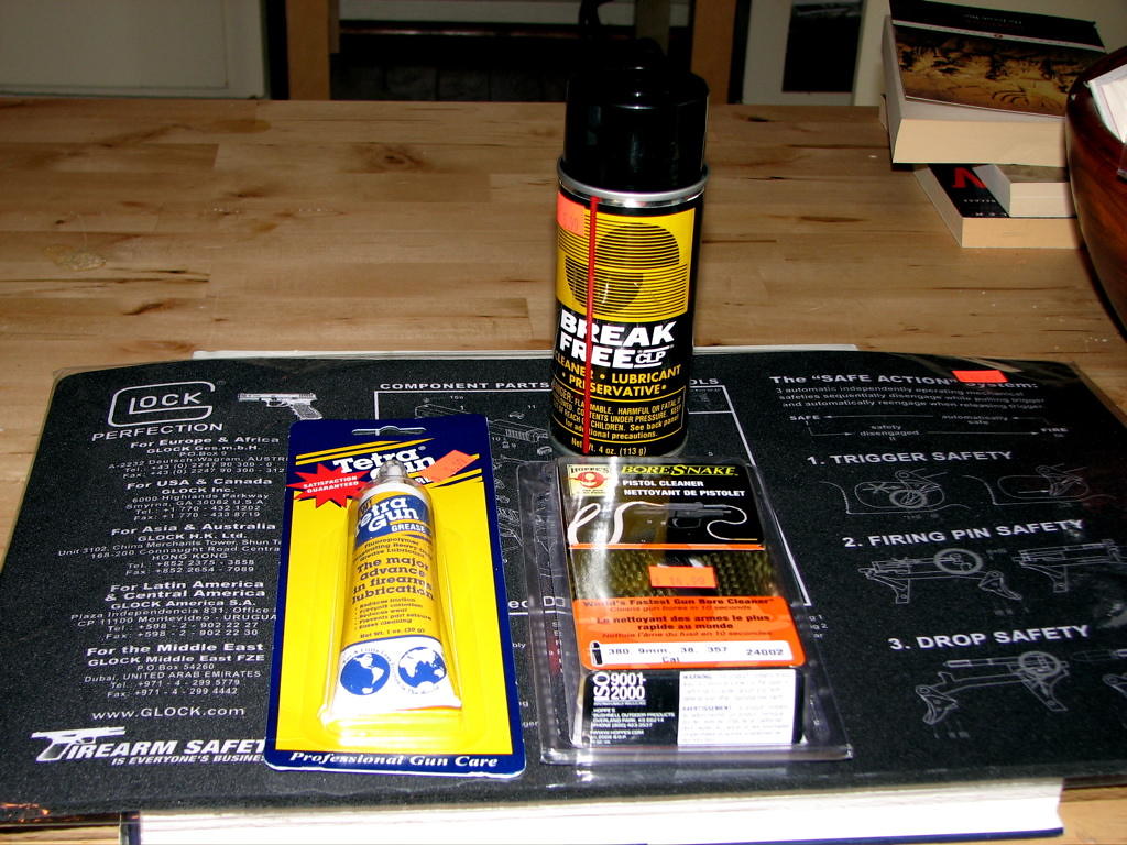 Handgun cleaning kit with solvent, brushes, and cleaning patches on a gun cleaning mat