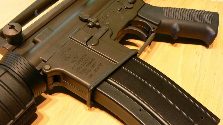 A semi-automatic AR-15 rifle resting on a table at a shooting range