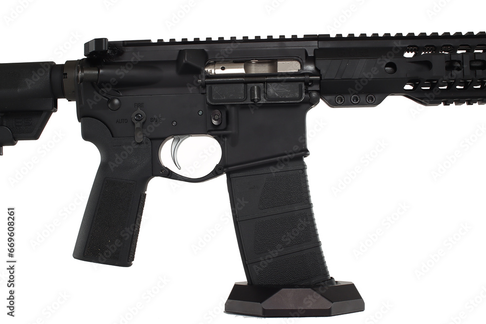 A modern AR-15 rifle with optics on a wooden workbench