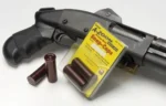 Pachmayr A-Zoom Metal Snap Caps .410 ga, two red snap caps and yellow package beside a black firearm