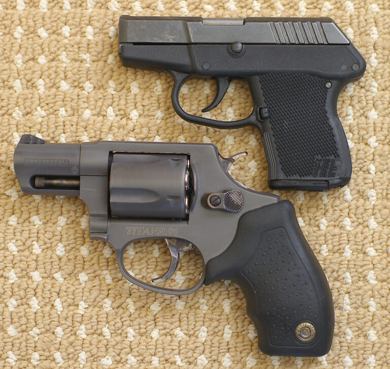 A silver revolver next to a black 9mm semi-automatic pistol on a wooden table