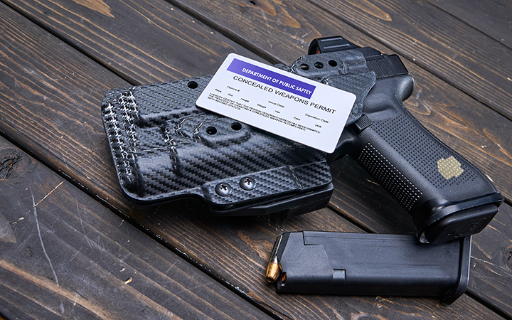 A compact 9mm handgun lying next to a spare magazine on a wooden surface