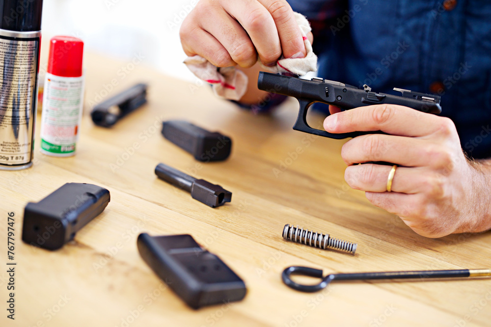 Close up of a person carefully cleaning a handgun on a wooden workbench