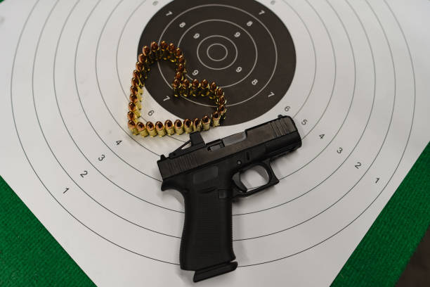 A 9mm semi-automatic pistol resting on a shooting bench with targets