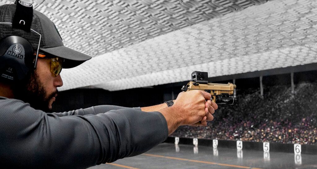 A modern semi-automatic pistol resting on a table with a rubber snap cap