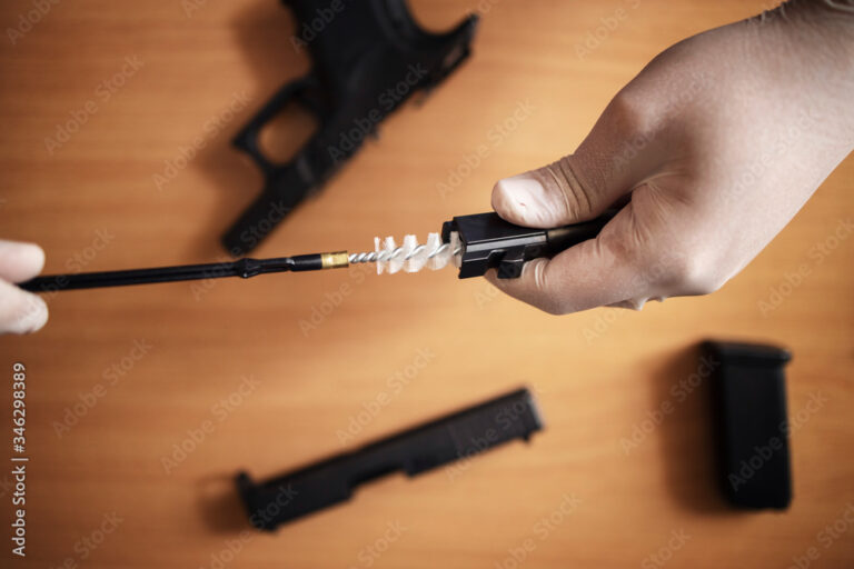 Person using a bronze brush and solvent to clean the inside of a rifle barrel