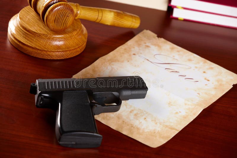 Gavel and legal documents next to a handgun on a desk
