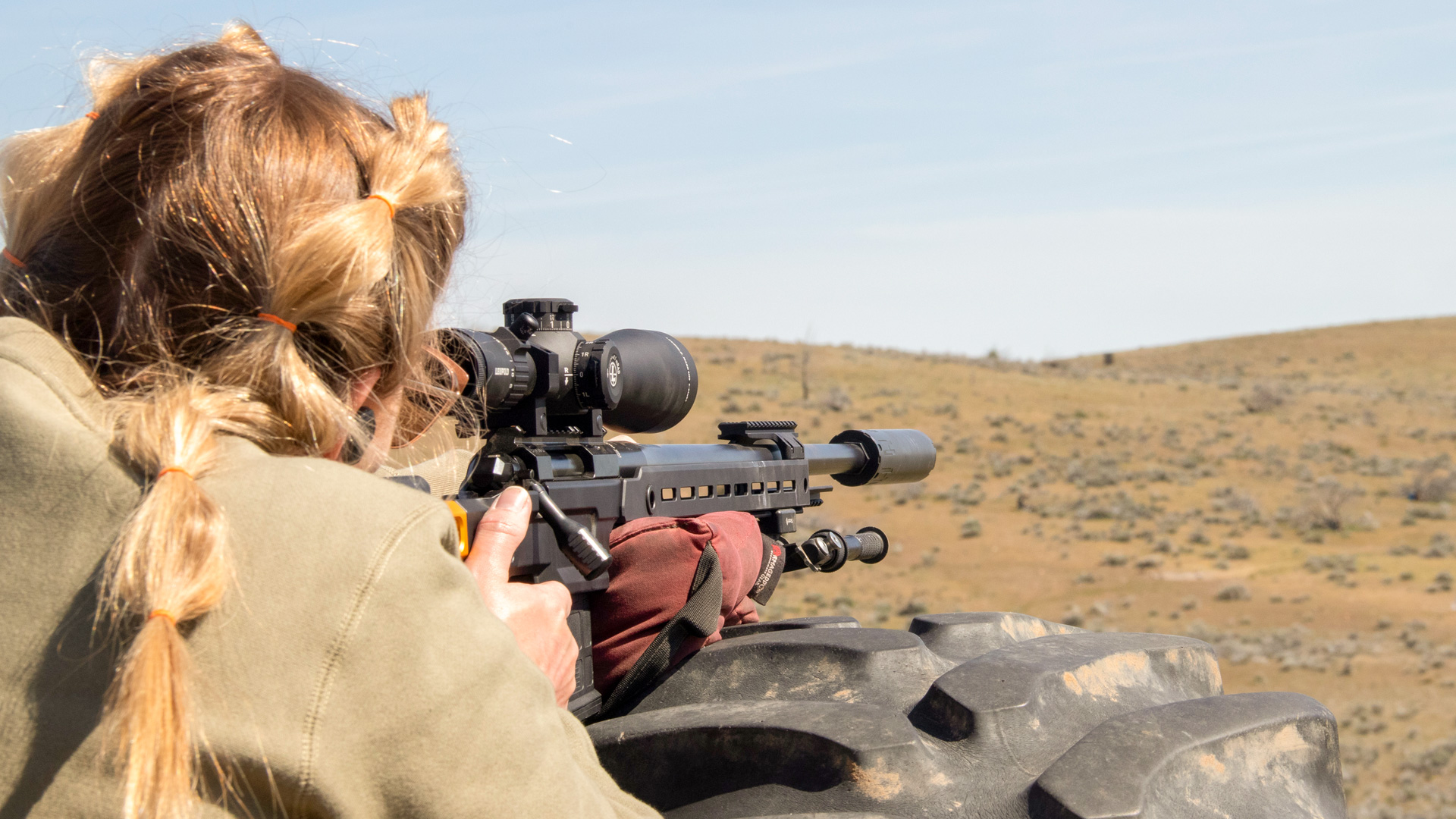 A marksman using a precision rifle with a sling at a shooting range