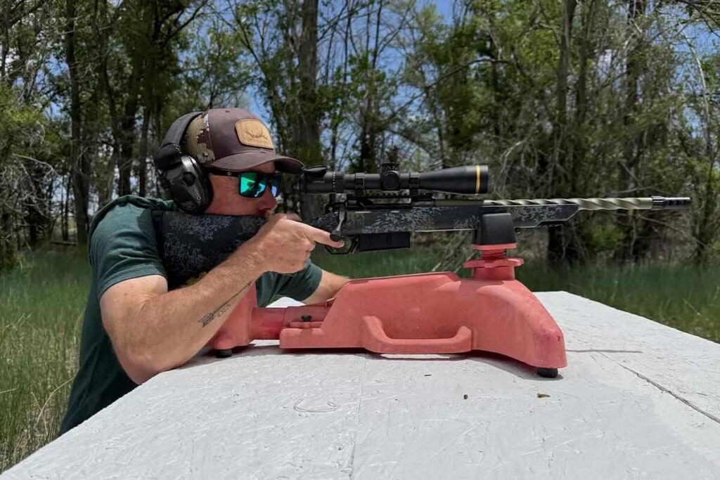 A precision bolt-action rifle chambered in 7mm PRC resting on a wooden shooting bench