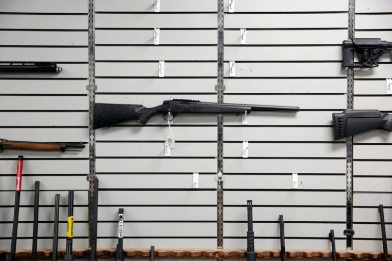 A person inspecting a handgun at a professional gun store counter