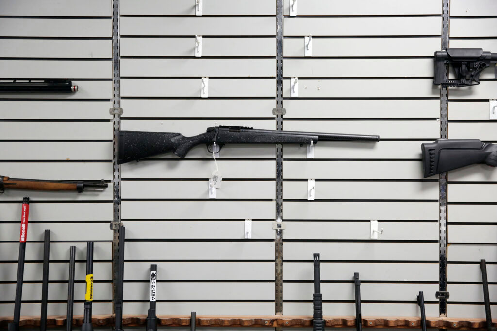 A person inspecting a handgun at a professional gun store counter