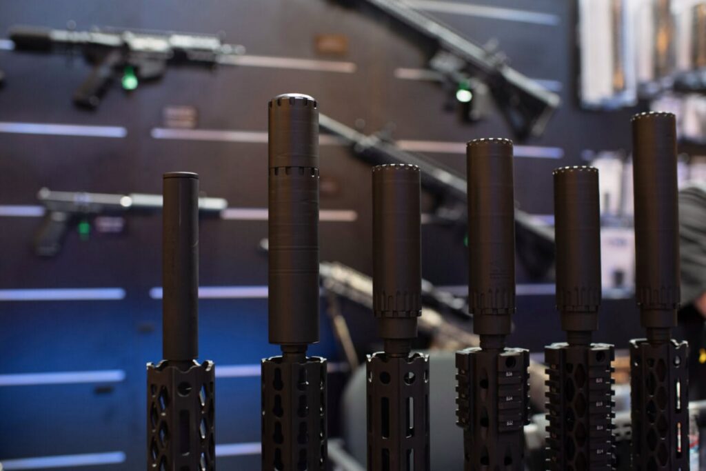 A modern rifle equipped with a suppressor resting on a wooden table