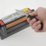 Smith's 6-inch Three Stone Sharpening System with knife held against orange stone