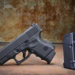 Pachmayr PKMYR GRIP EXTENDER FOR GLK 26 +XL black pistol beside an upright magazine