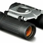 Konus BASIC compact binocular black and silver, angled front view with orange-tinted lenses