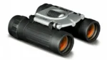 Konus BASIC compact binocular black and silver, angled front view with orange-tinted lenses