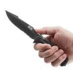 SOG SEAL Strike Knife, black blade and handle held in hand with partial serrations visible