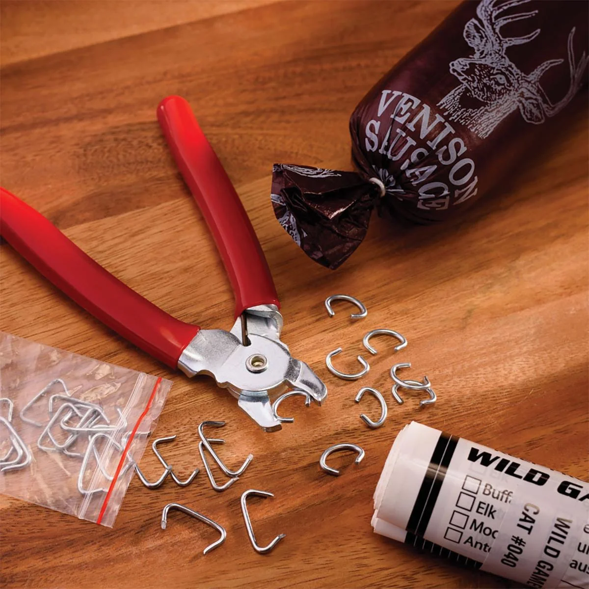 primary-40125 LEM Products 3/8-inch Hog Rings, silver rings beside red-handled pliers on a wood surface