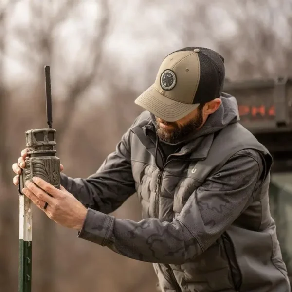 Gsm StealthCam Revolver Pro, man holding a tall green and black trail camera outdoors
