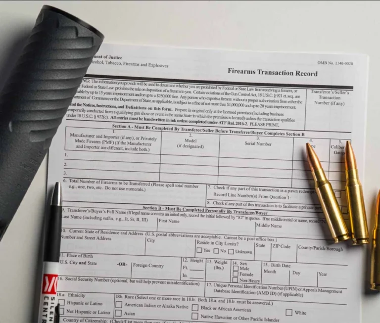 Suppressor and short-barreled rifle beside federal NFA application paperwork