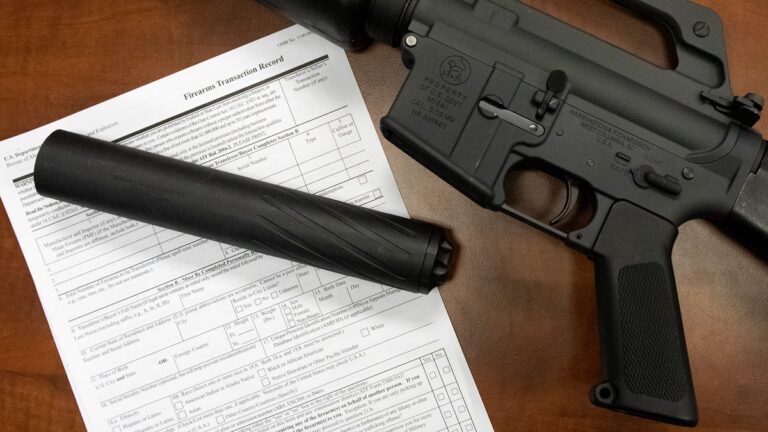 Firearm suppressor beside paperwork illustrating DOJ NFA ruling and gun ownership requirements