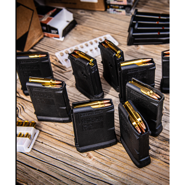 Double-stack pistol magazine beside an unloaded handgun on a shooting bench