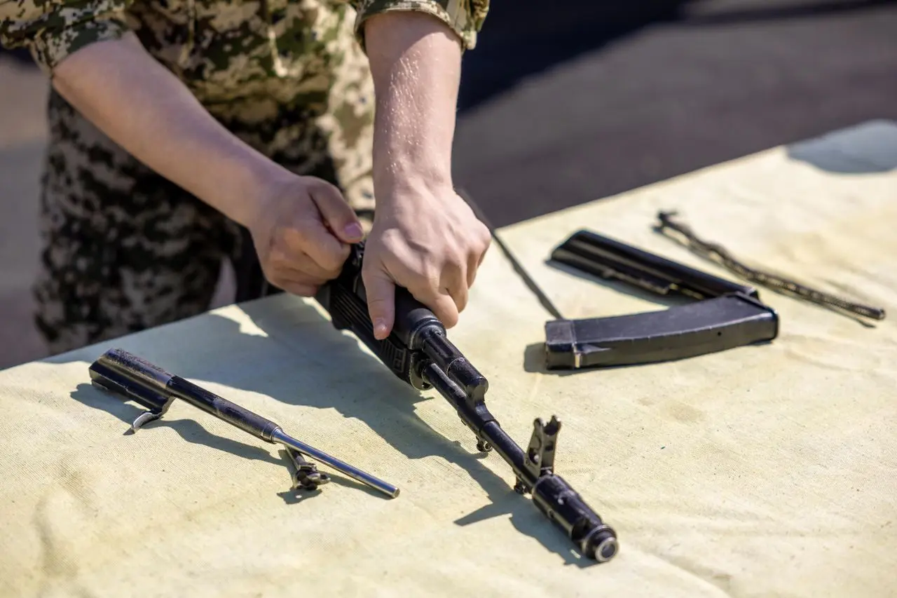 A person assembling a rifle at a table