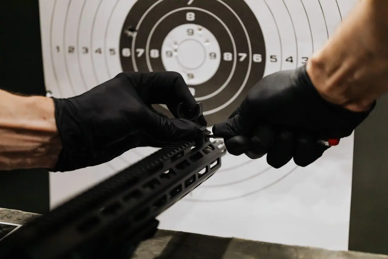 Gloved hands adjusting the iron sight on a rifle